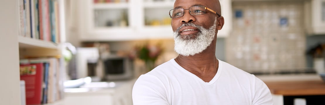 Man sits in a kitchen looking out a window